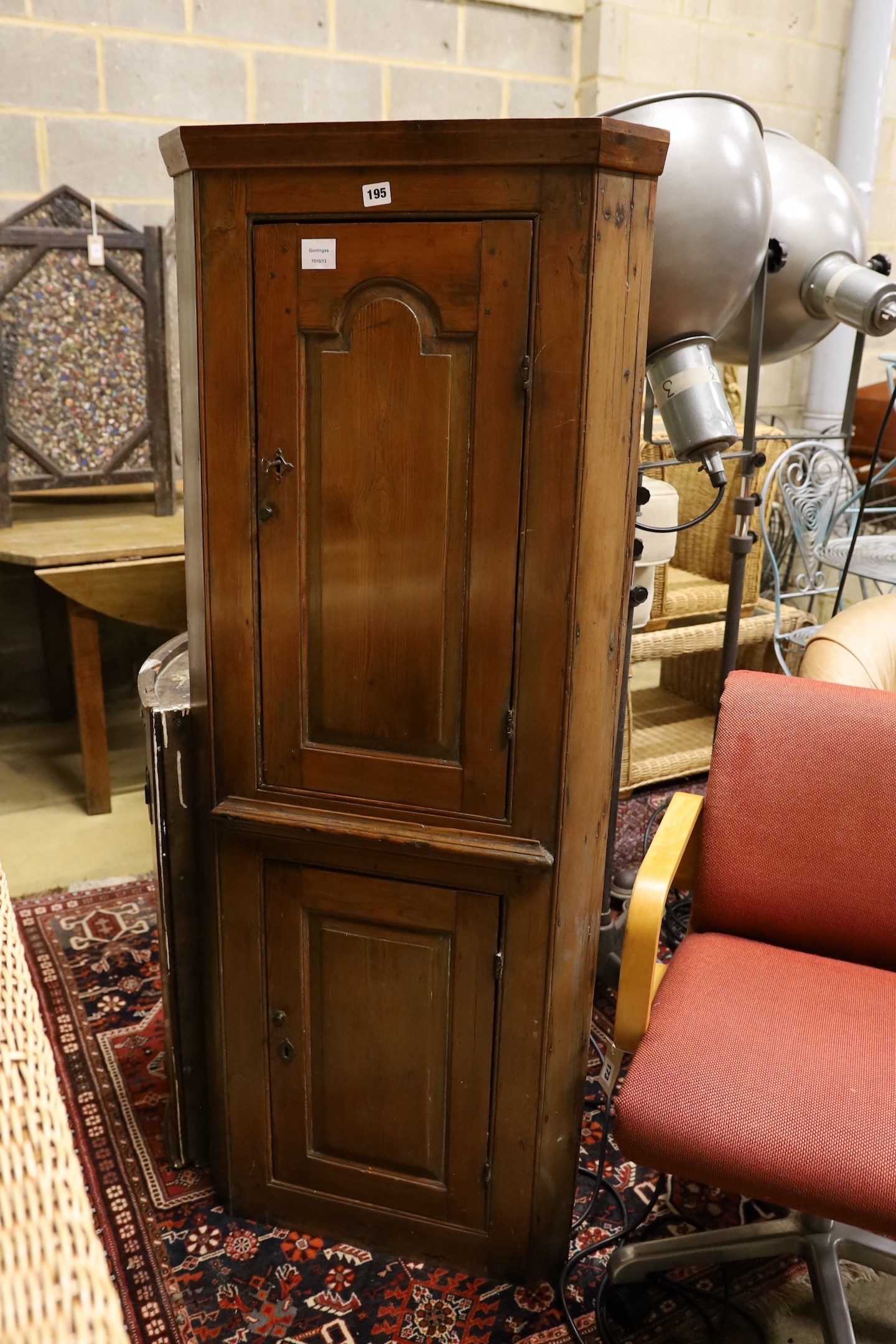 A small early 19th century pine two door standing corner cabinet, (lacking back leg) width 58cm, depth 30cm, height 150cm